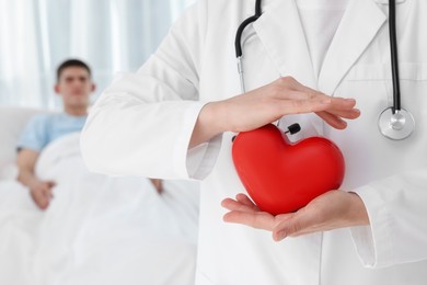 Photo of Doctor holding red heart in clinic, selective focus