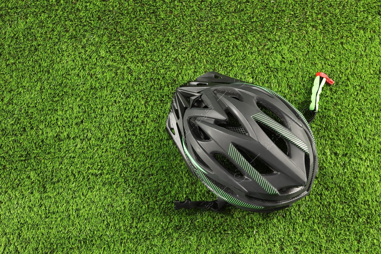 Photo of Stylish protective helmet on green grass, top view. Space for text