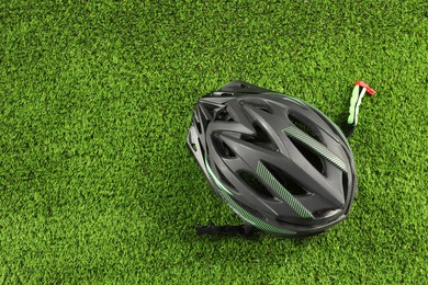 Stylish protective helmet on green grass, top view. Space for text
