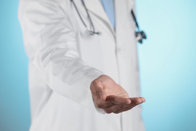 Photo of Doctor holding something on light blue background, closeup