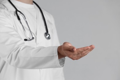 Doctor holding something on grey background, closeup