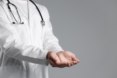 Photo of Doctor holding something on grey background, closeup. Space for text