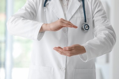 Doctor with stethoscope holding something in clinic, closeup