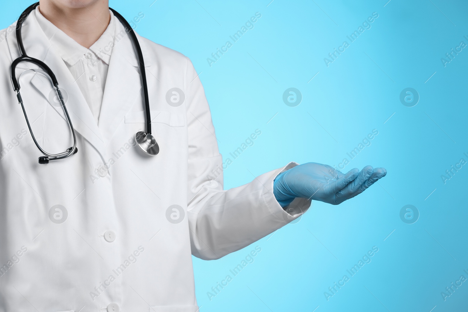 Photo of Doctor holding something on light blue background, closeup