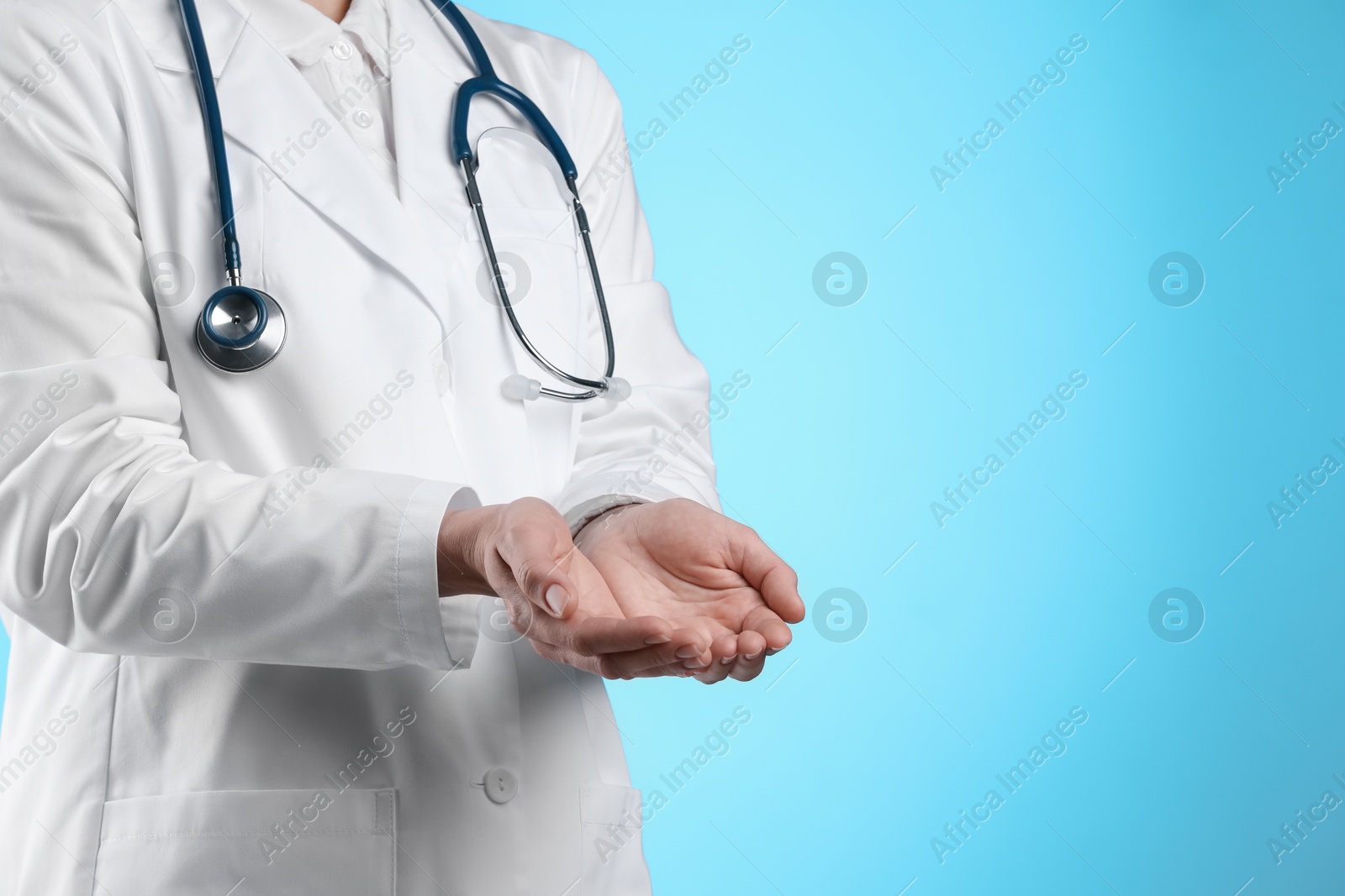 Photo of Doctor holding something on light blue background, closeup. Space for text