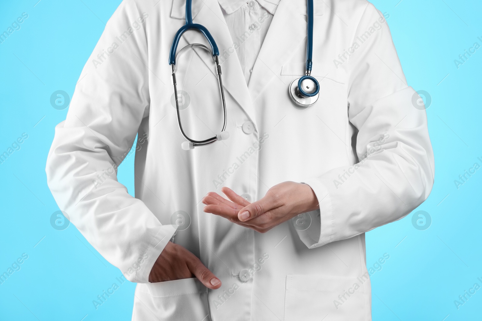 Photo of Doctor holding something on light blue background, closeup