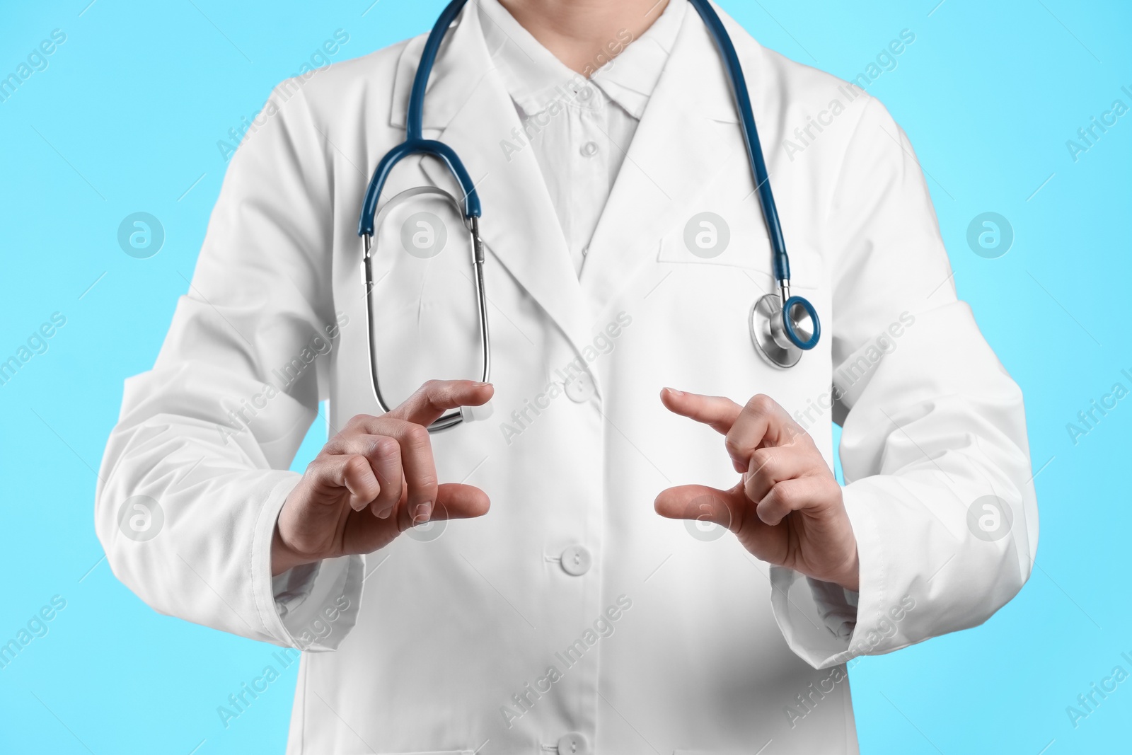 Photo of Doctor holding something on light blue background, closeup