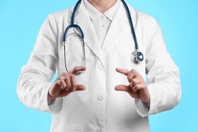 Doctor holding something on light blue background, closeup