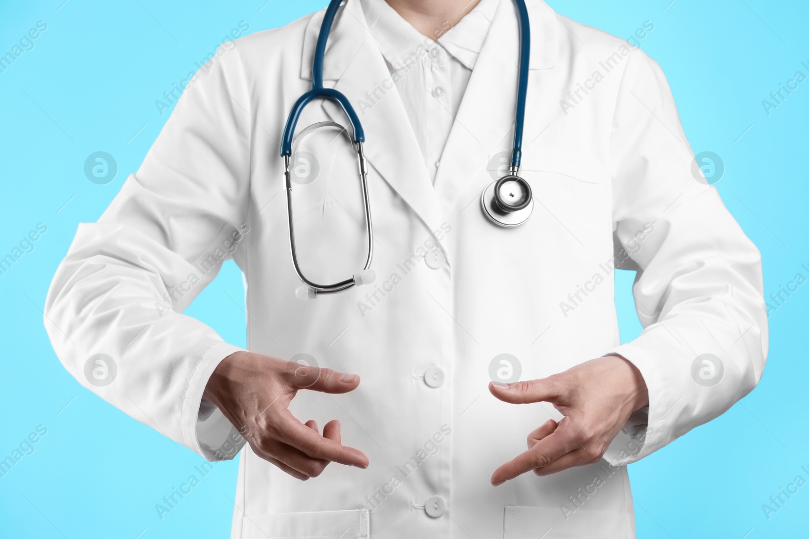 Photo of Doctor holding something on light blue background, closeup