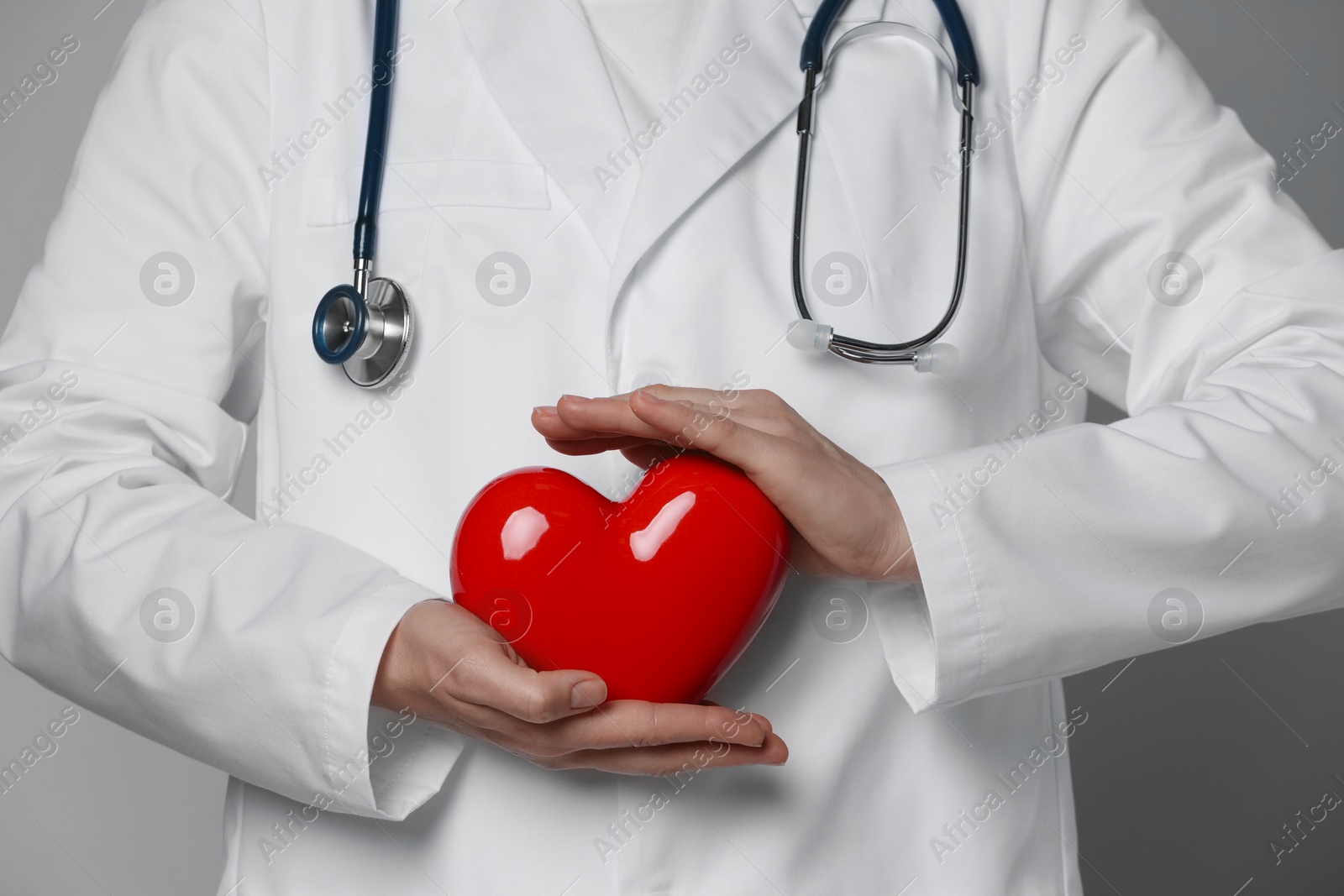 Photo of Doctor with red heart on grey background, closeup