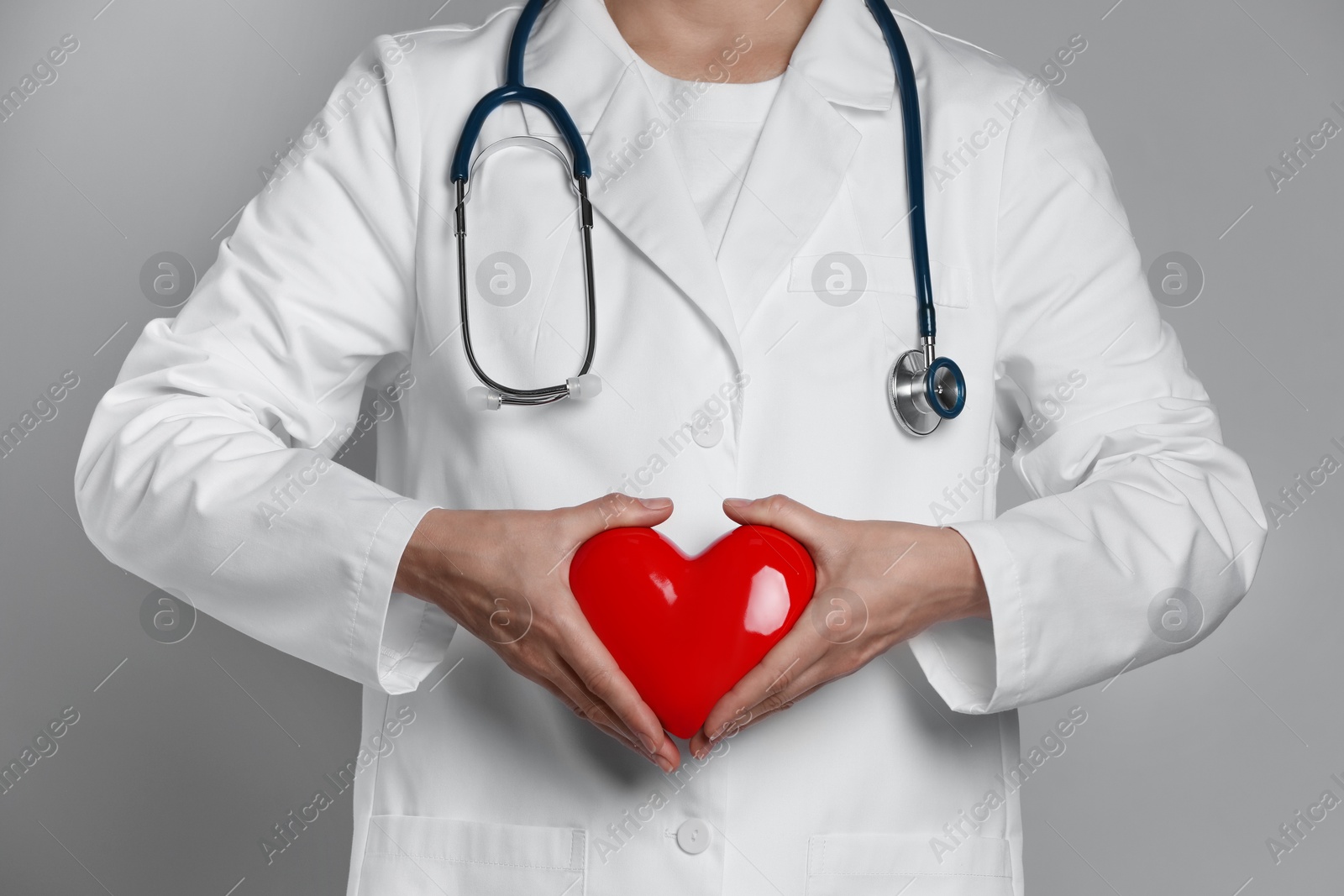 Photo of Doctor with red heart on grey background, closeup