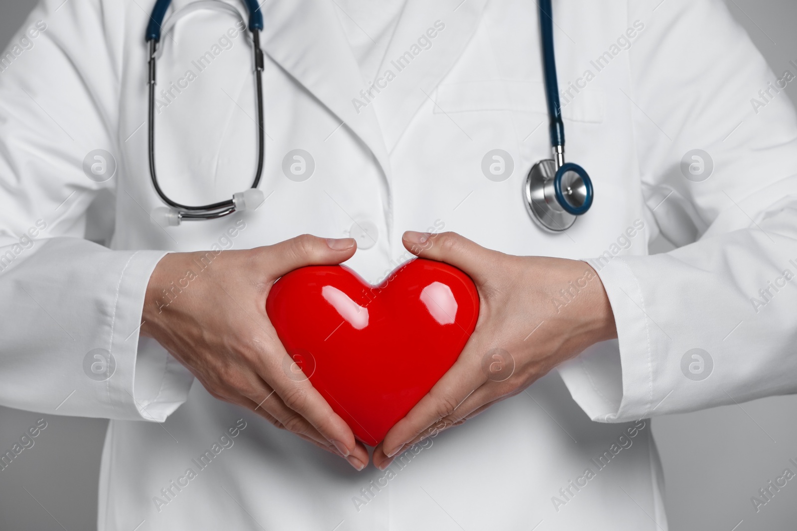 Photo of Doctor with red heart on grey background, closeup