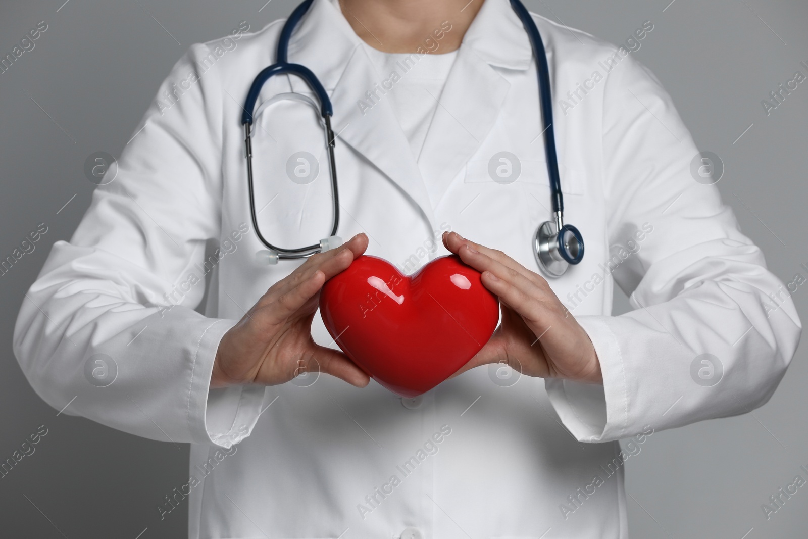 Photo of Doctor with red heart on grey background, closeup