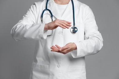 Photo of Doctor holding something on grey background, closeup