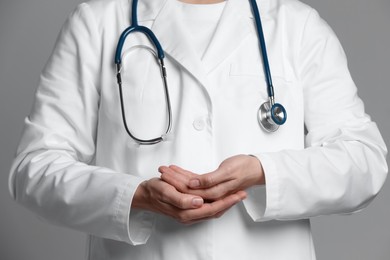 Doctor holding something on grey background, closeup