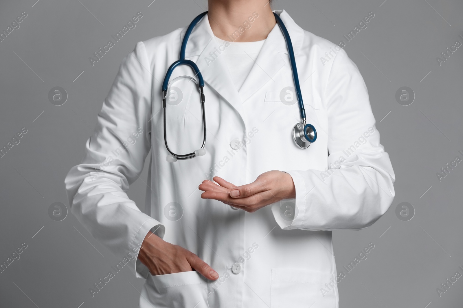 Photo of Doctor holding something on grey background, closeup