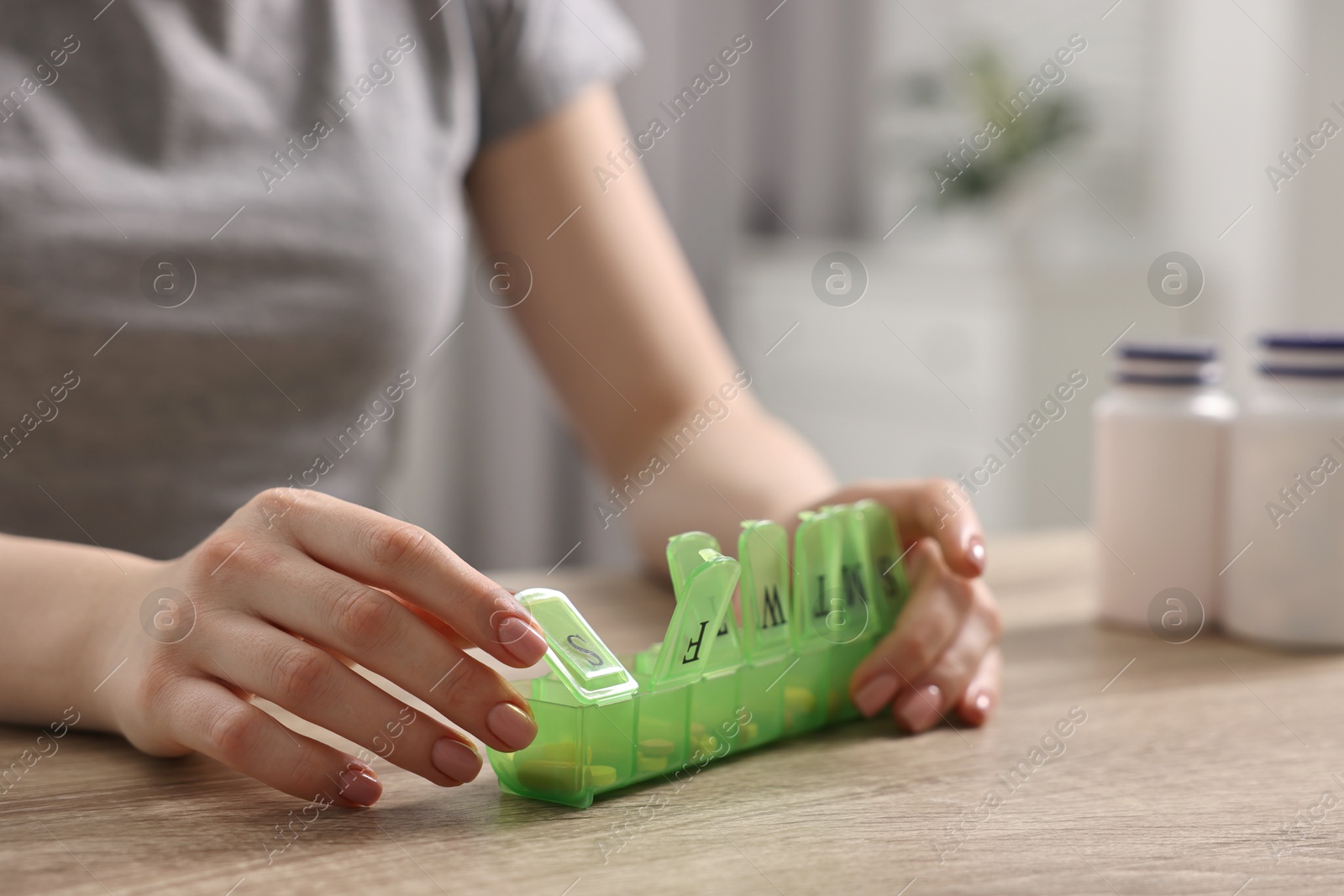 Photo of Woman with pills and organizer at wooden table, closeup