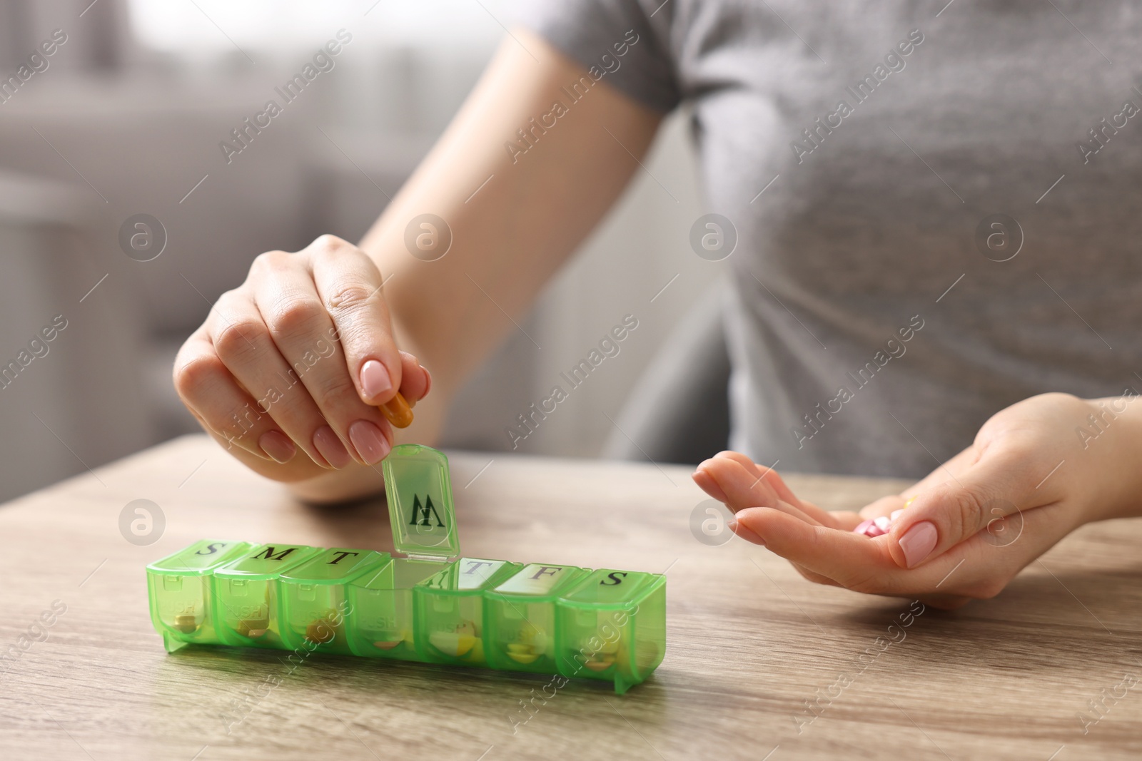 Photo of Woman with pills and organizer at wooden table, closeup