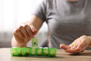 Photo of Woman with pills and organizer at wooden table, closeup