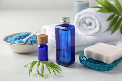 Photo of Spa composition. Cosmetic products, soap, towels and sea salt on light table