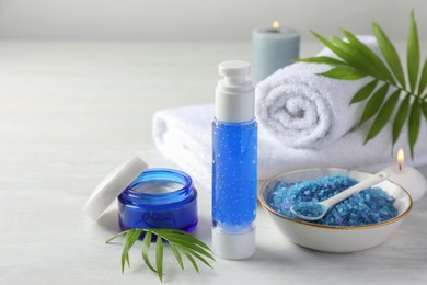 Photo of Spa composition. Cosmetic products, towels, sea salt and burning candles on light table