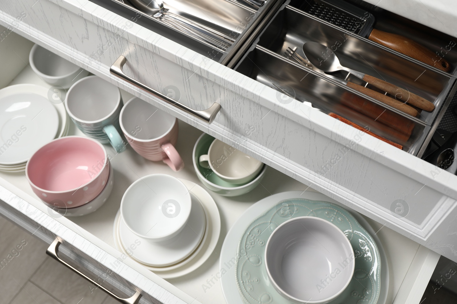 Photo of Ceramic dishware and cutlery in drawers indoors, above view