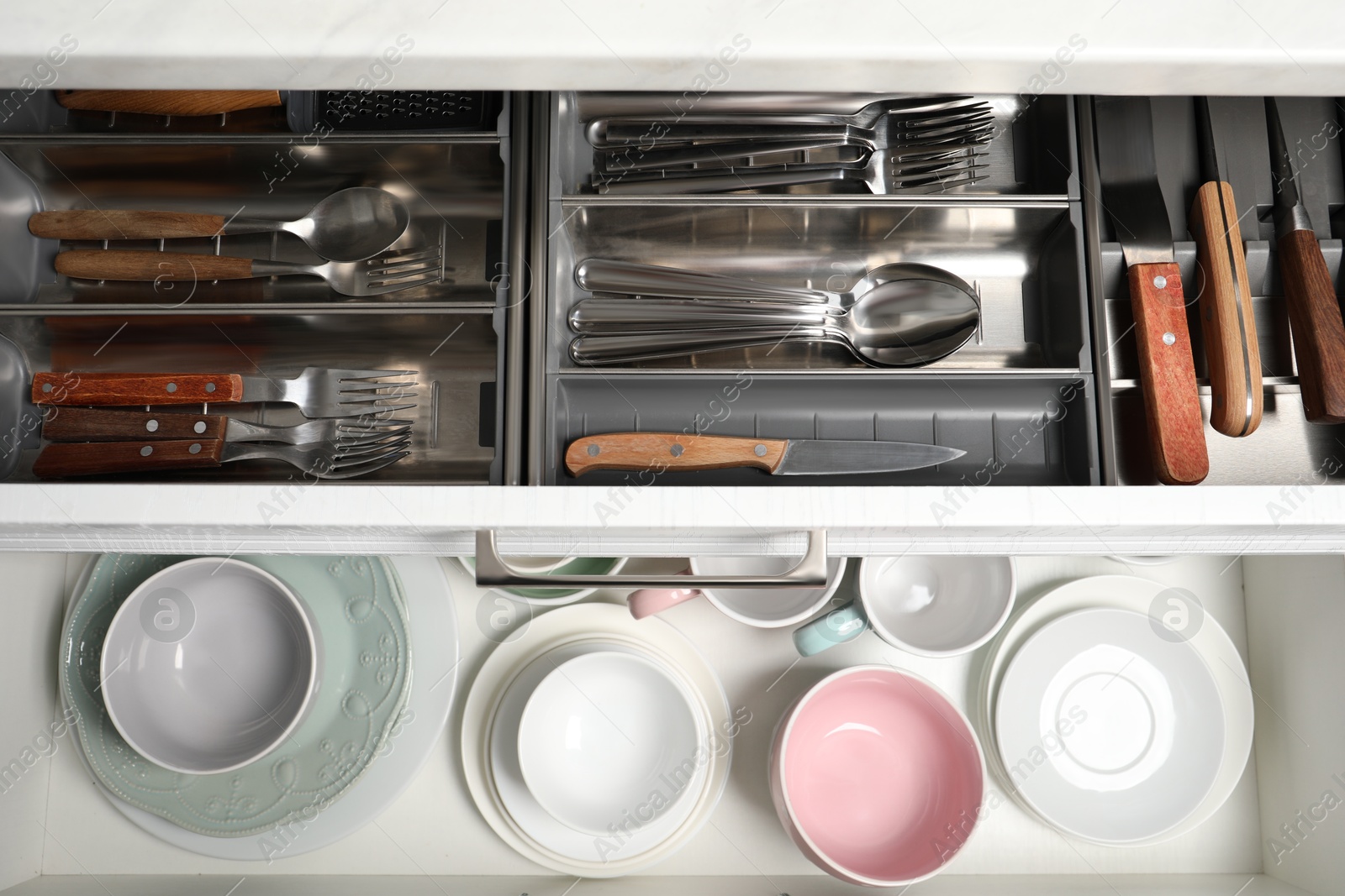 Photo of Clean plates, bowls and cutlery in drawers, top view