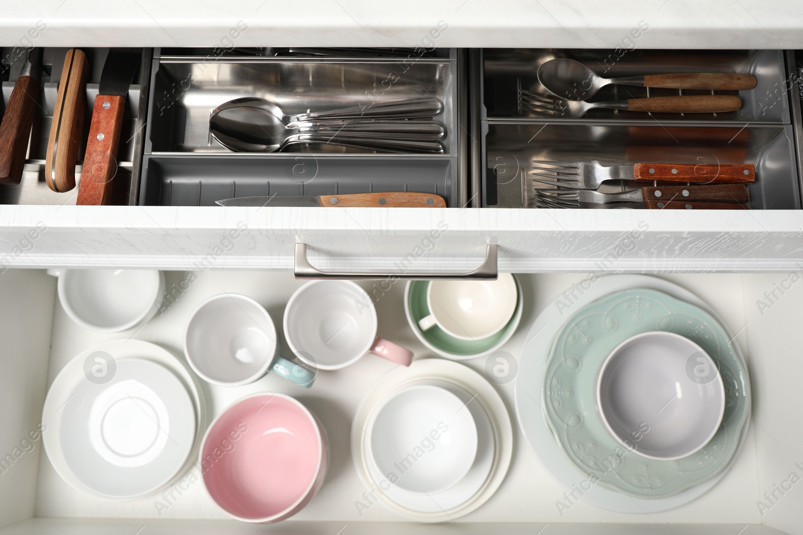 Photo of Clean plates, bowls and cutlery in drawers, top view