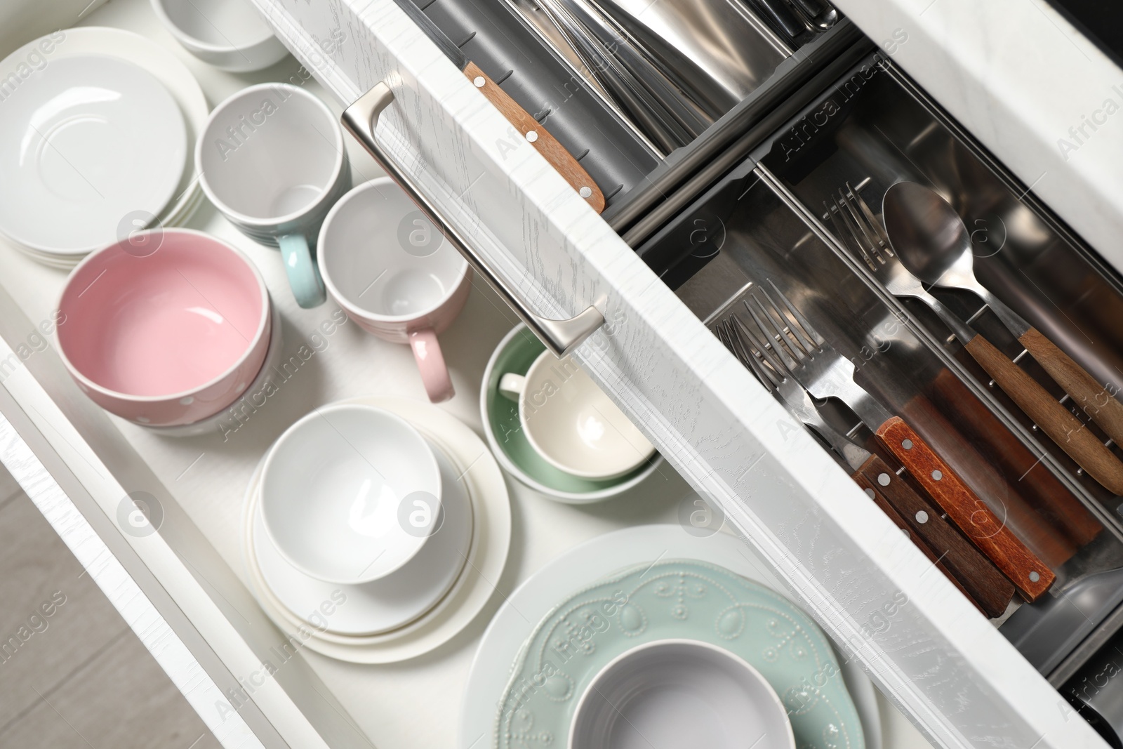 Photo of Ceramic dishware and cutlery in drawers indoors, above view