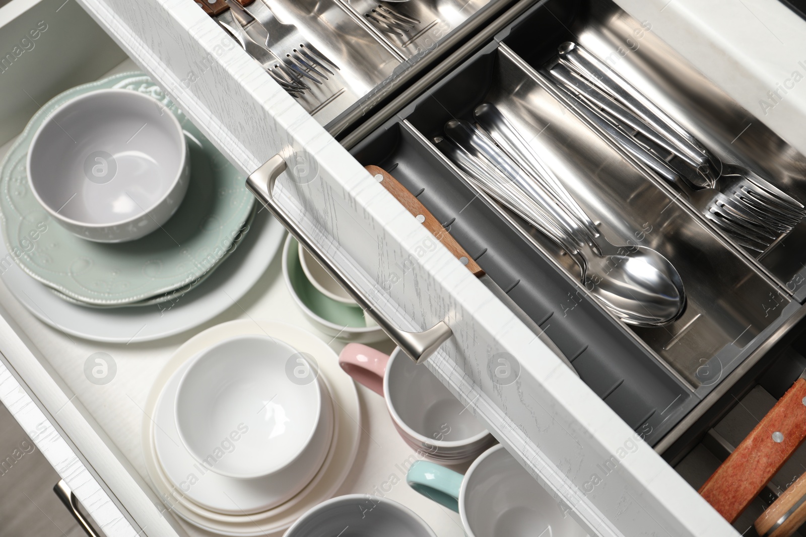 Photo of Ceramic dishware and cutlery in drawers indoors, above view