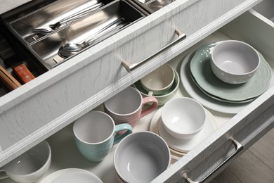 Photo of Ceramic dishware and cutlery in drawers indoors