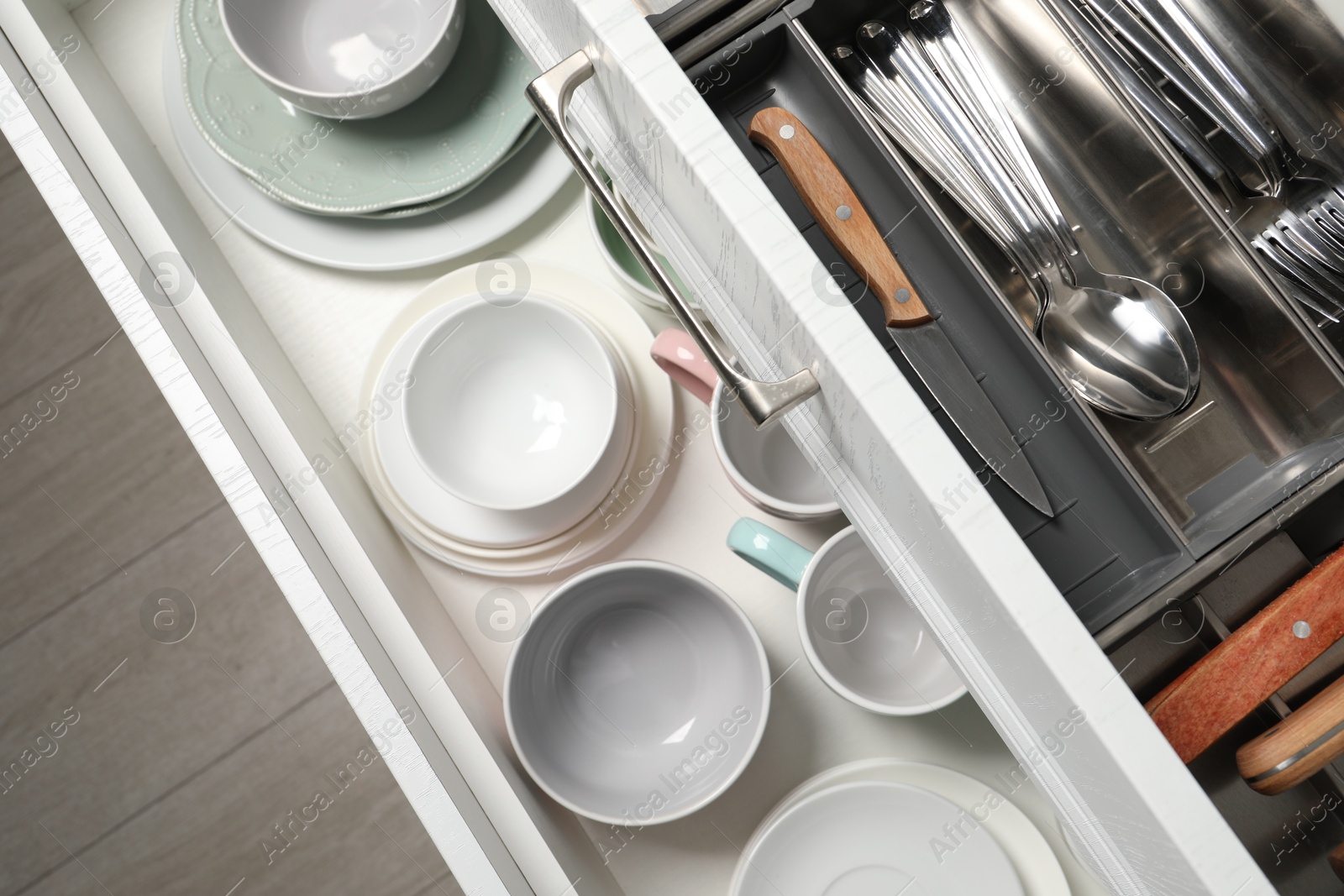 Photo of Ceramic dishware and cutlery in drawers indoors, above view