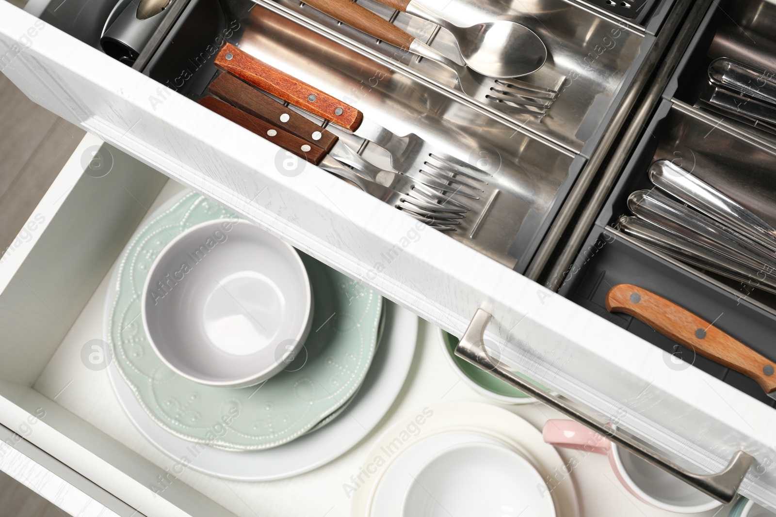 Photo of Ceramic dishware and cutlery in drawers, above view