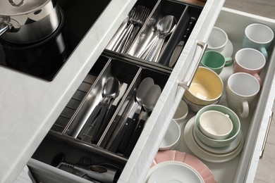 Ceramic dishware and cutlery in drawers indoors