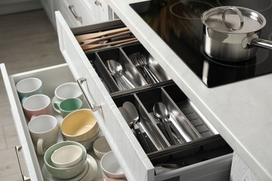 Ceramic dishware and cutlery in drawers in kitchen