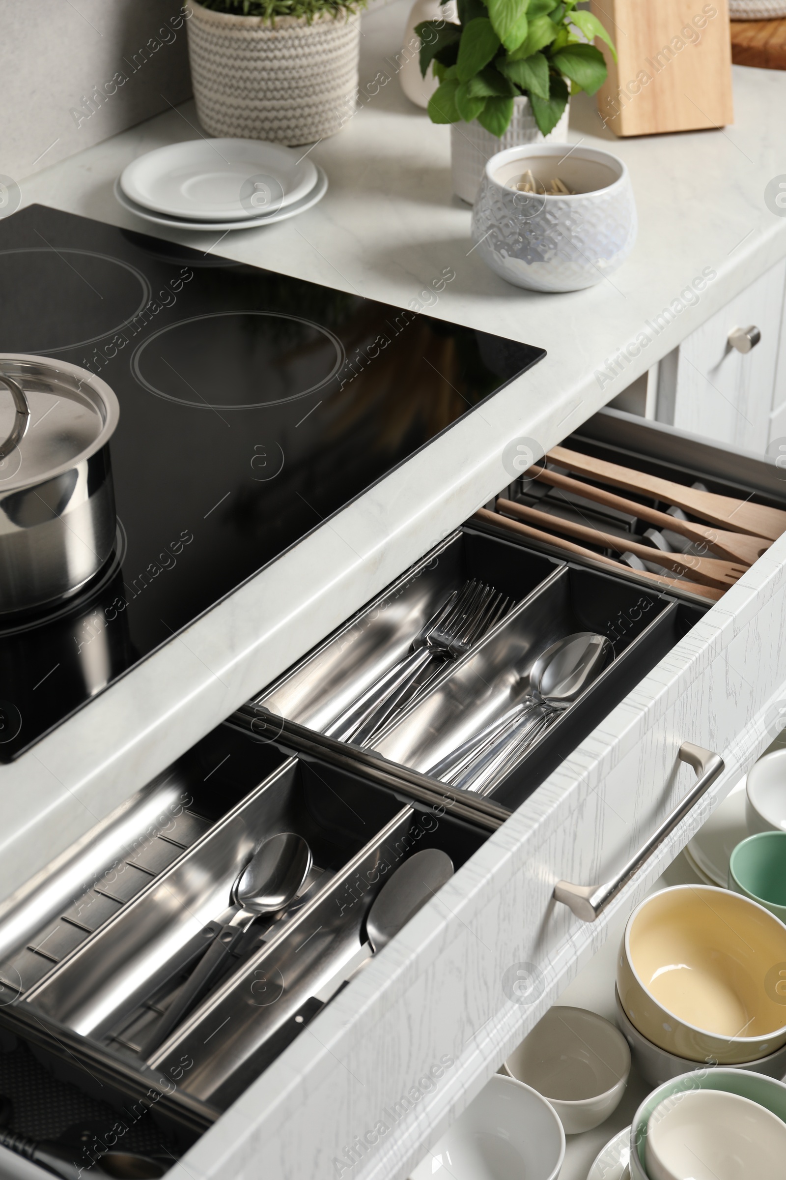 Photo of Ceramic dishware and cutlery in drawers in kitchen