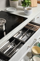 Ceramic dishware and cutlery in drawers in kitchen