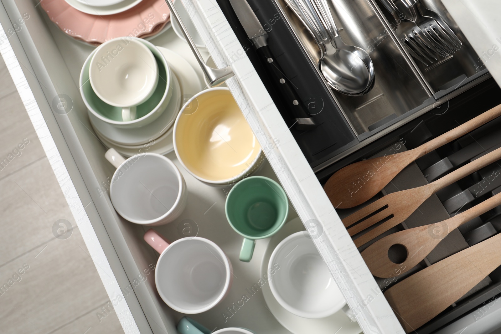 Photo of Ceramic dishware, utensils and cutlery in drawers, top view