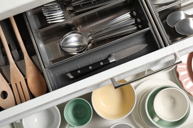 Ceramic dishware and cutlery in drawers, top view