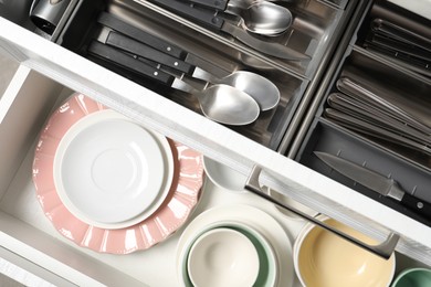 Photo of Ceramic dishware and cutlery in drawers, top view