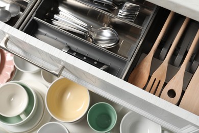 Photo of Ceramic dishware, utensils and cutlery in drawers, top view