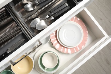 Photo of Ceramic dishware and cutlery in drawers indoors, top view