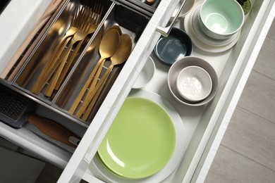 Ceramic dishware and cutlery in drawers indoors, top view