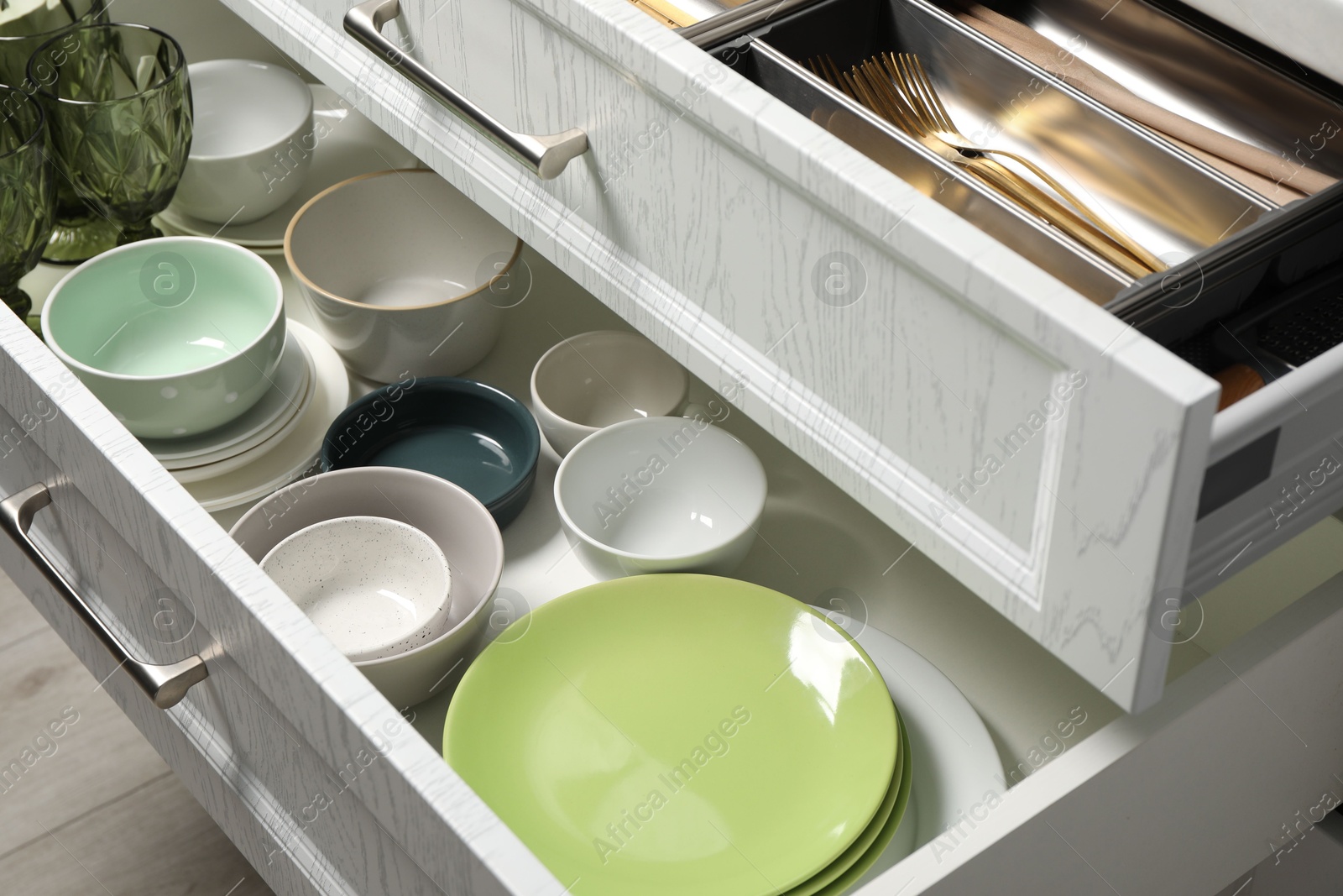 Photo of Ceramic dishware and cutlery in drawers indoors