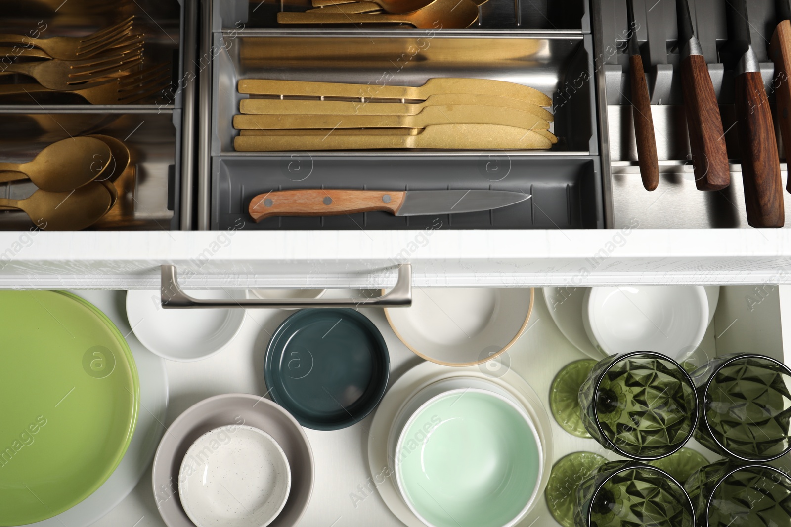 Photo of Ceramic dishware and cutlery in drawers indoors, top view