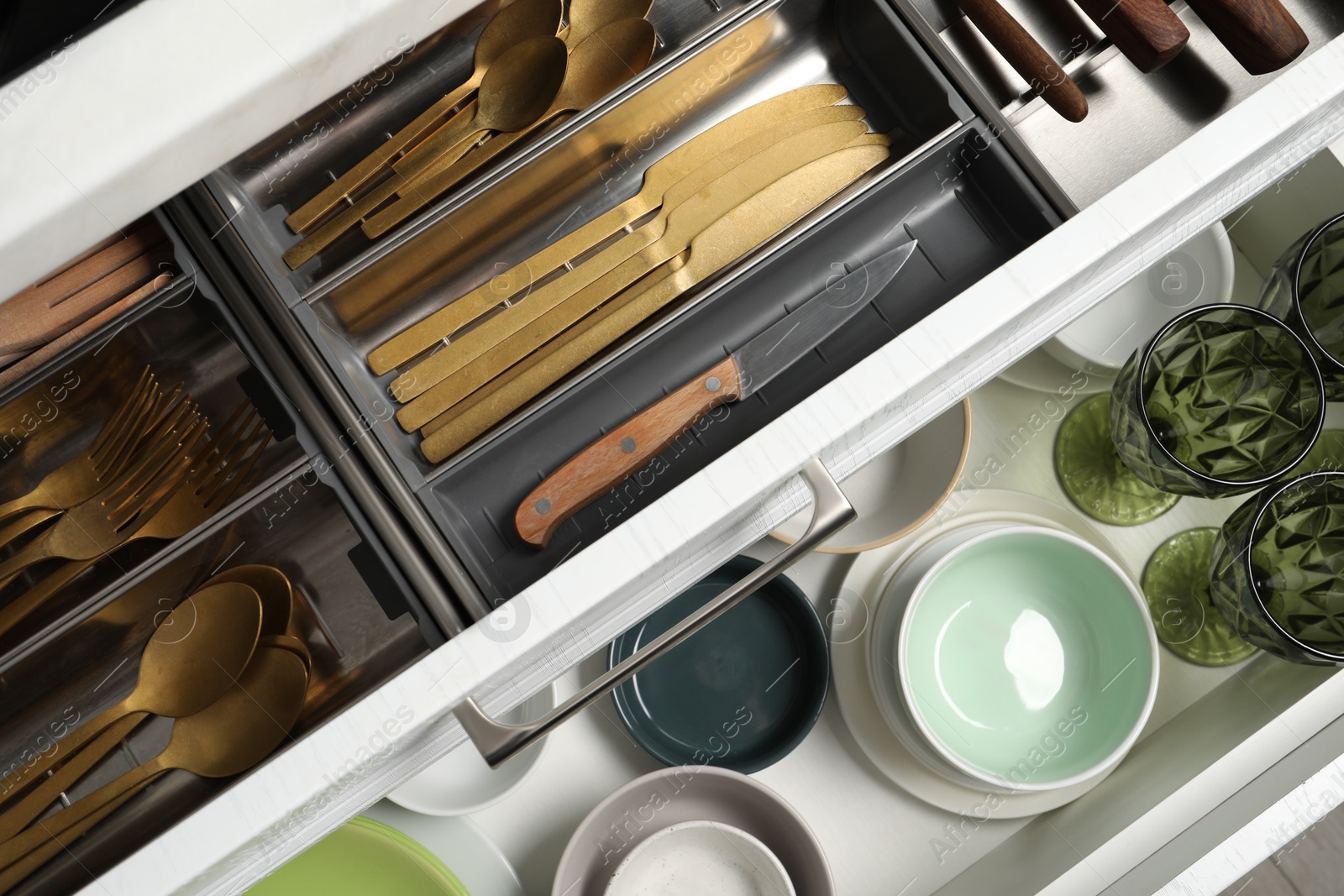 Photo of Ceramic dishware and cutlery in drawers indoors, top view