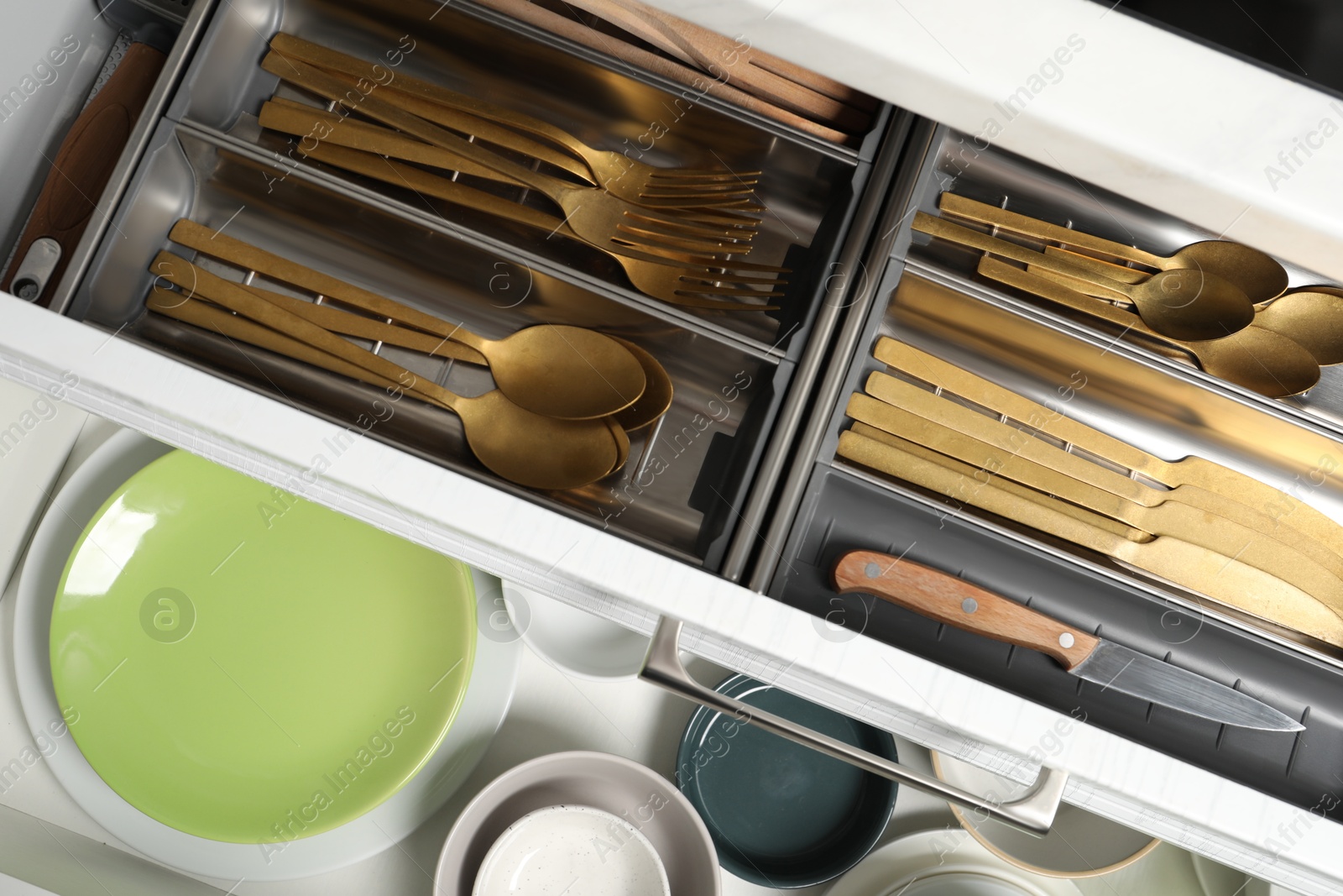 Photo of Ceramic dishware and cutlery in drawers indoors, top view