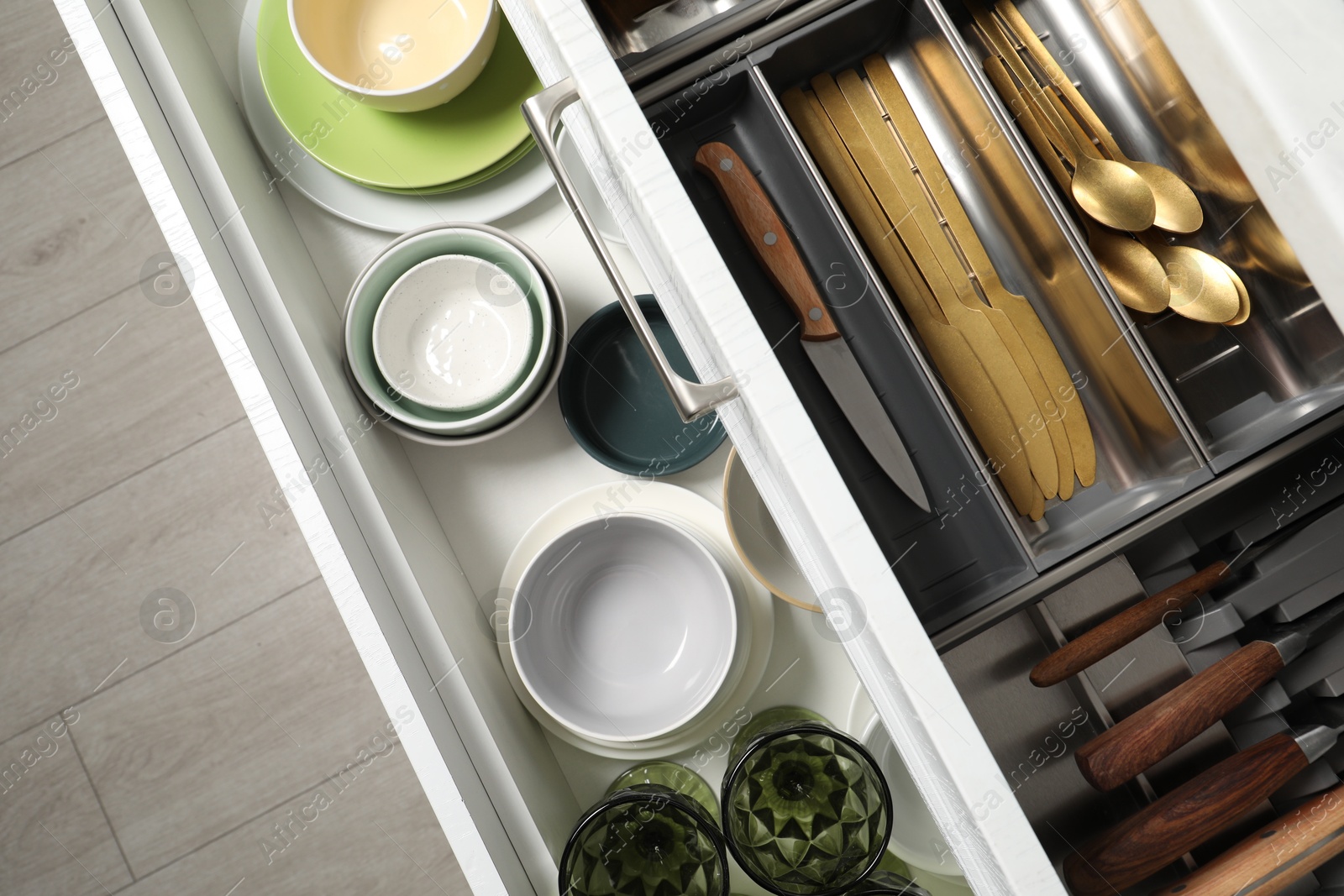 Photo of Ceramic dishware and cutlery in drawers indoors, top view