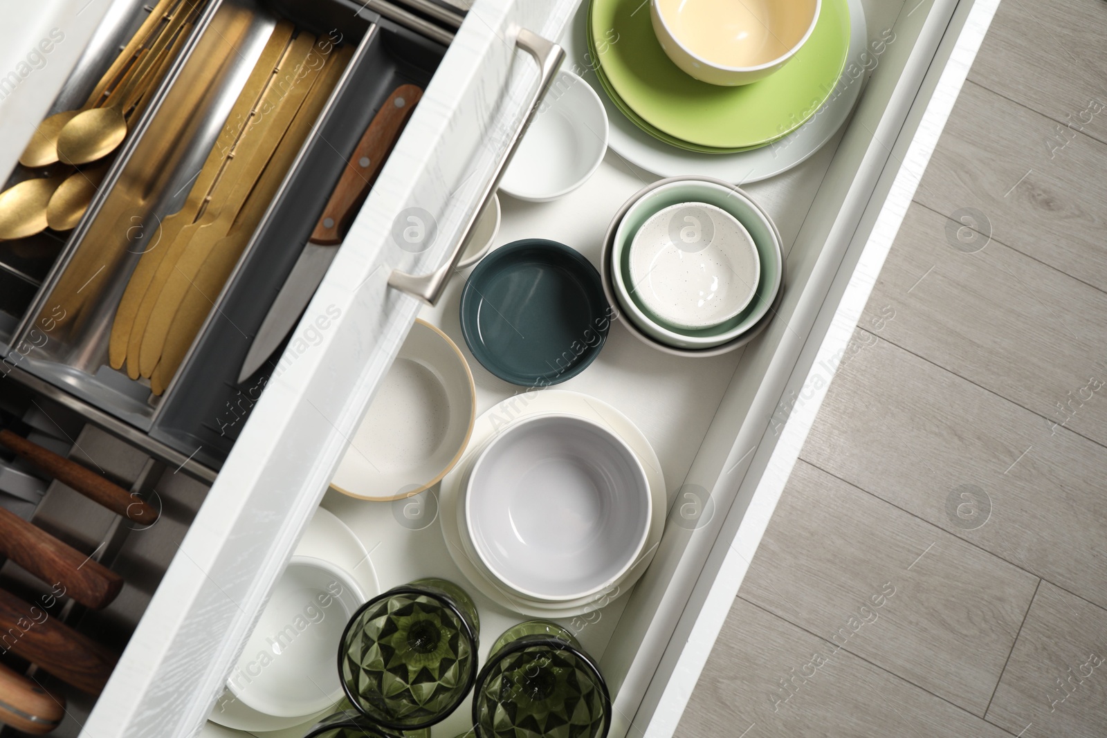 Photo of Ceramic dishware and cutlery in drawers indoors, top view