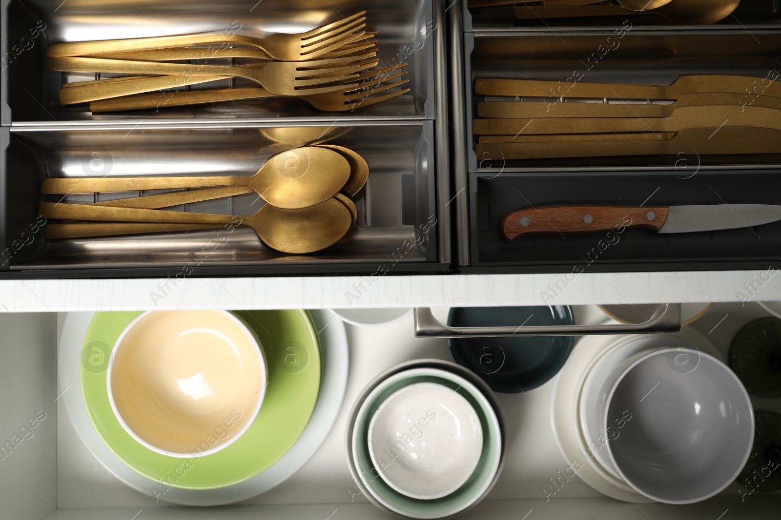 Photo of Ceramic dishware and cutlery in drawers indoors, top view